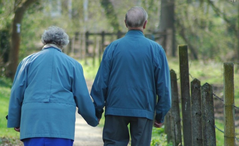 Elderly couple holding hands and walking