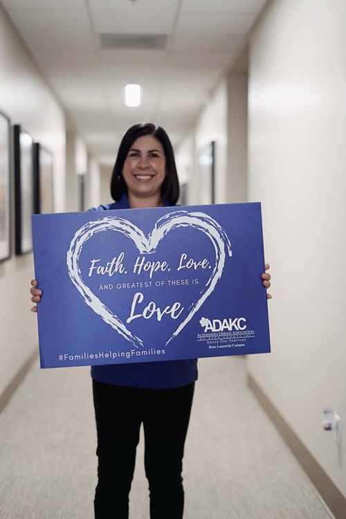 ADAKC Director Janelle Capra holding a Faith Hope Love sign