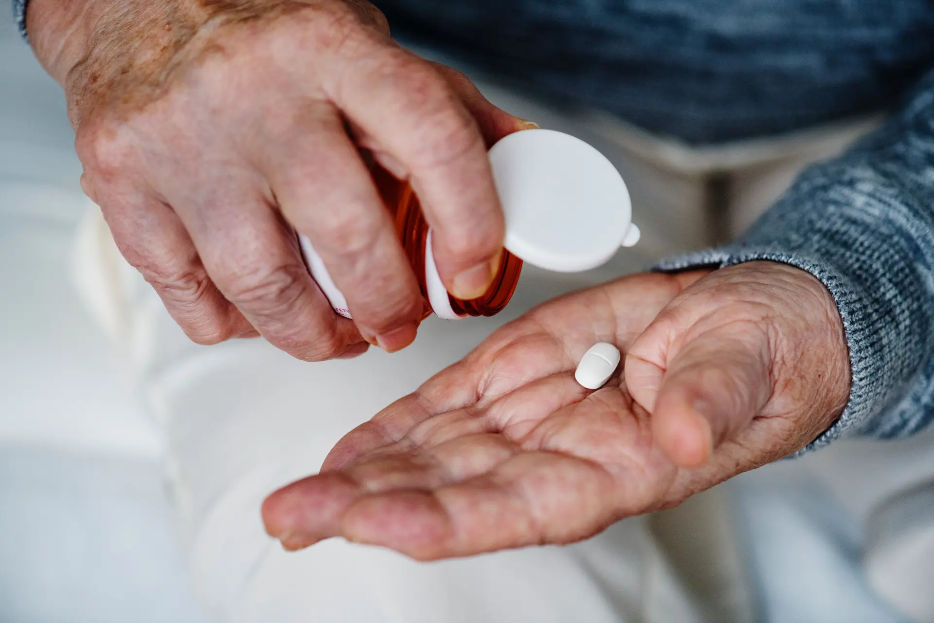 Person pouring medication into their hand from a pill bottle